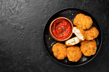 Delicious crispy fried breaded chicken patties with sauce on black background. top view