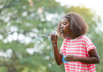 African American girl playing with soap bubbles in the park