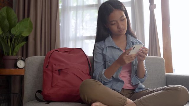 teenage girl using smartphone while sitting in living room