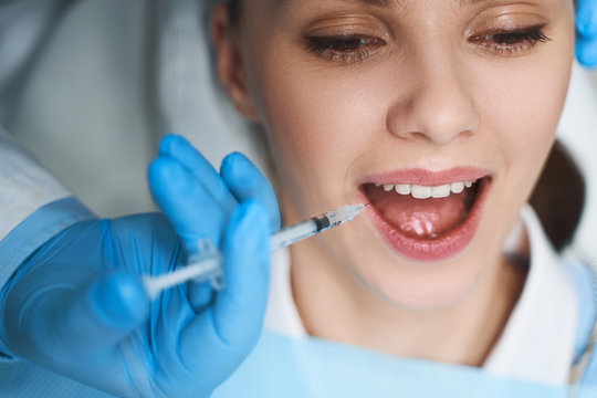 Woman getting injection into mouth stock photo