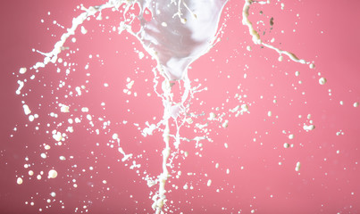 Splashing milk on a pink background.