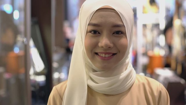 Close Up Portrait of a Young Asian Muslim Woman dressing in the traditional Hijab looking at camera smiling confidently