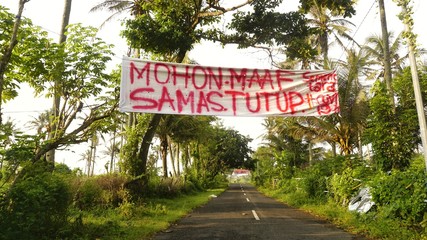 Yogyakarta, Indonesia - April 4, 2020: Road in the coastal area of Yogyakarta that is closed to prevent the spread of Corona Covid-19 Virus. Spanned banner containing a prohibition of entering / cross