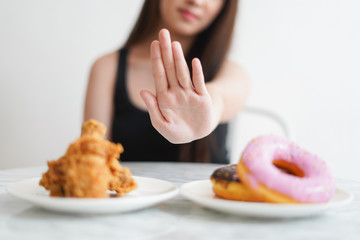 Obraz na płótnie Canvas Young woman refuse and say no to eat junk food or unhealthy food as donut and fry chicken to diet and loss weight high calories food control