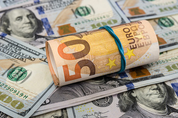 50 euros rolled into a roll on a background of dollars