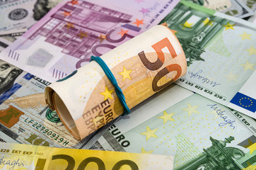 50 euros twisted into a roll on a background of euro banknotes. Money background.