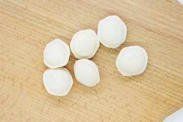 Frozen raw dumplings located on a wooden board