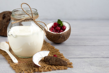 Homemade yogurt in a glass jar on a wooden light background with a ceramic spoon. Healthy diet food. Vegetarian food.