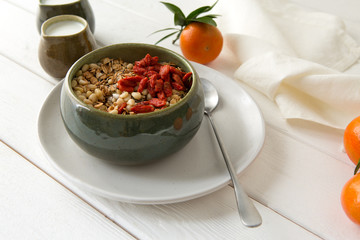 bowl with granola, yogurt in jugs and tangerines on a light table