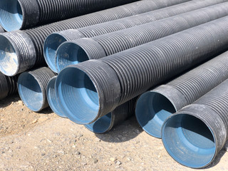 Stacked corrugated pvc-pipes at the outdoor warehouse. Drainage, plumbing, stormwater equipment