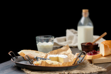 Rustic country breakfast with brie cheese, milk, baguette and cranberry jam