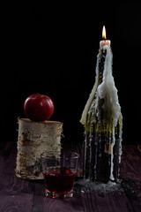 A bottle of wine with a candle and an Apple