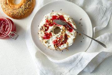 plate with bagels with cream cheese and raspberry jam on a light table