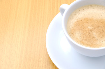 Coffee cup on wooden kitchen table. Top view with morning sunlight