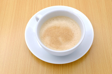 Coffee cup on wooden kitchen table. Top view with morning sunlight