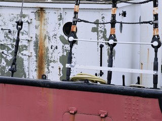 Partial view of a red side wall and white deck superstructure of a ship. Aspiring shrouds are...
