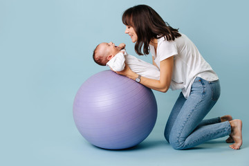 Young mom plays with infant on fitness ball