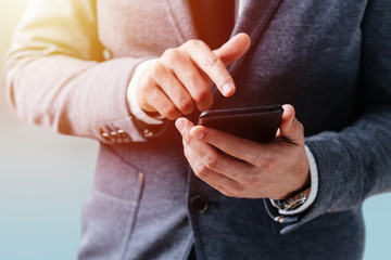 The businessman holds the phone in his hands and presses the screen