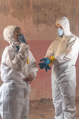 Couple of scientists virologists getting dressed with a full white protection and insulation...