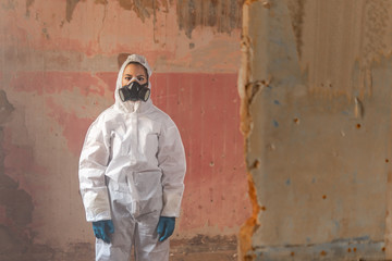 Young virologist doctor woman wearing a white biohazard protection suit and and a gas mask during...
