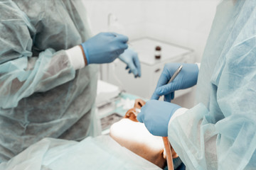 Naklejka na ściany i meble Dentists will perform an operation, implant placement. Real operation. Tooth extraction, implants. Professional uniform and equipment of a dentist. Healthcare Equipping a doctor’s workplace. Dentistry