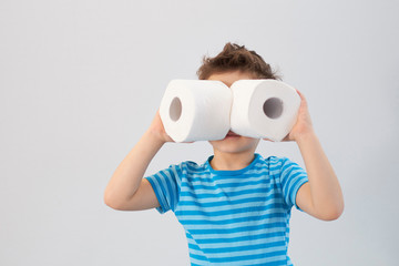 Active boy playing with toilet paper in retro filter,kid boy looking through toilet roll,Child holding two white tissue, Children health care concept