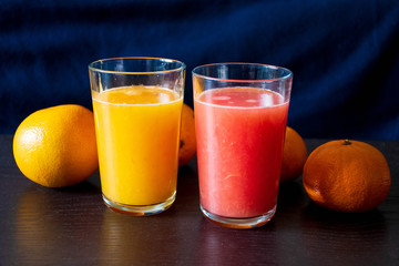 Healthy orange juice and grapefruit juice in glass cups with black background 