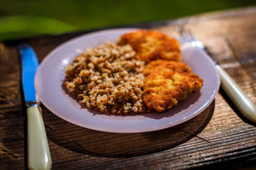 Chicken schnitzel with buckwheat on plate over wooden background. Top view, flat lay.