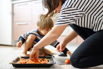 happy family make food at home. mom together her four year old kid son toddler cooking pizza in the kitchen. concept pastimes of isolation time in quarantine mode during coronavirus covid-19