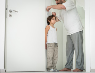 Father measuring the height of his son