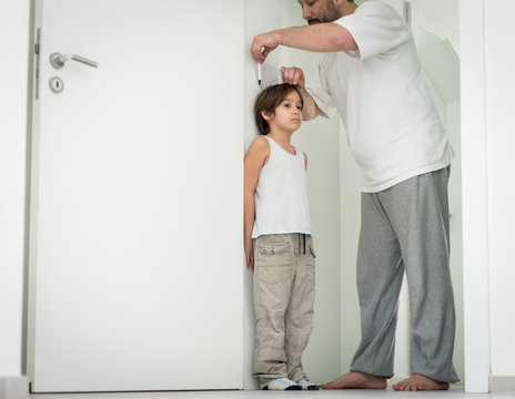 Father Measuring The Height Of His Son