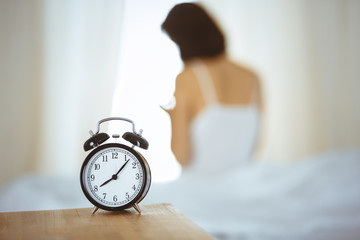 Woman stretching hands in bed after wake up, sun flare . Brunette entering a day happy and relaxed after good night sleep and back view. Concept of a new day and joyful weekend