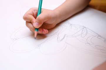 kids hobby. child hand draws sketch with a pencil on white paper