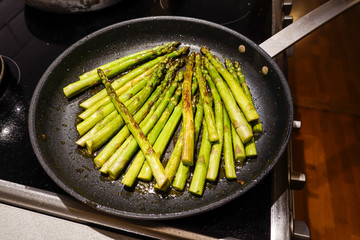 Fresh green asparagus frying in a pan with olive oil