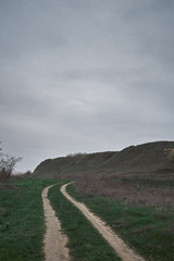 Fototapeta na wymiar dramatic country road in the green hills mountains with grey sky. Dnieper Bug Canal Ukraine