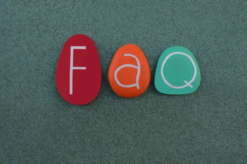 FAQ, Frequently Asket Question text composed with colored stone letters over green sand