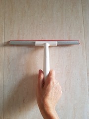 Closeup of lady using water repellent rubber brush to clean tile wall copy space.
Housewares concept.