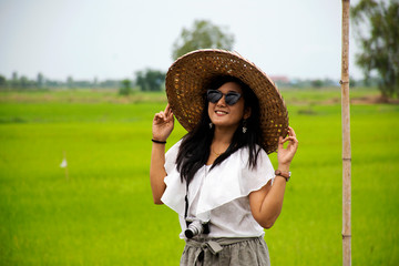 Travelers thai woman posing portrait for take photo with bamboo hat vietnam style at outdoor and garden rice field at cafe coffee shop in Ayutthaya, Thailand