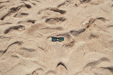 sunglasses in the center of shiny beach sand