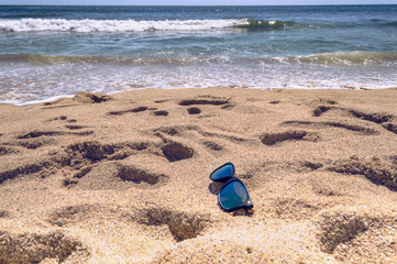 sunglasses lying near sea on sunny day