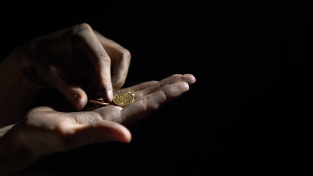 Euro Coins Falling Into The Dirty Hands Of A Man, A Worker Recounts Money On A Black Background In The Darkness