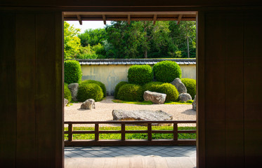 The beautiful Japanese rock garden in Hamilton, New Zealand look through wooden door. Rock garden is a type of garden which suggests mountains and water using only stones, sand or gravel and plants.