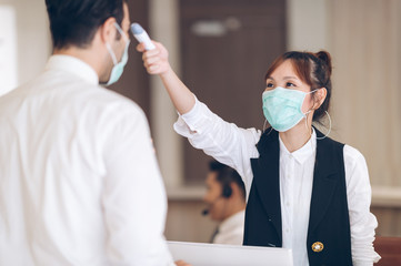 mask protect Coronavirus - Local building officials check the temperature with a thermometer before entering the building