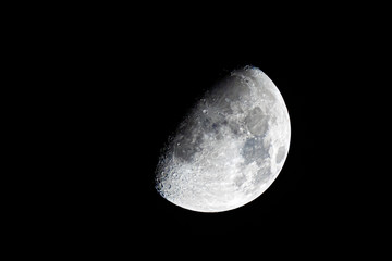 Half moon during the first quarter phase isolated against a black sky at night