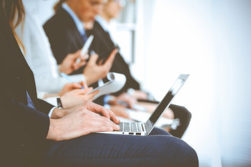 Business people working at meeting or conference, close-up of hands. Group of unknown businessmen and women in modern white office. Teamwork or coaching concept