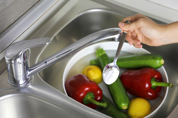 COVID-19 Pandemic Coronavirus Close up woman hands washing vegetables with baking soda to prevent...