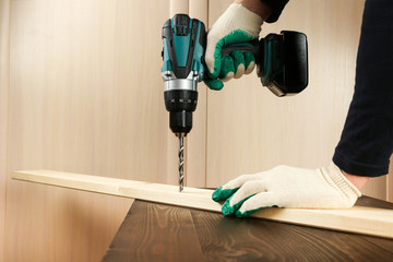 worker's hand is drilling wood plank by cordless drill close up with copy space