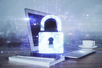 Double exposure of desktop with computer and lock icon hologram. Concept of data safety.