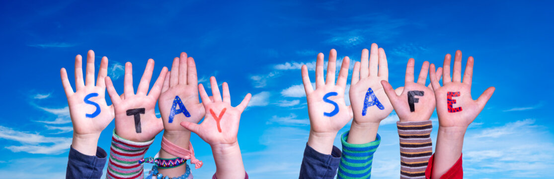 Kids Hands Holding Colorful English Word Stay Safe. Blue Sky As Background
