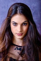 Naklejka premium black hair woman portrait with brown eyes on a gray background , Caucasian ethnic group is looking into the camera with a serious expression on her face. White girl with long black hair and brown eye